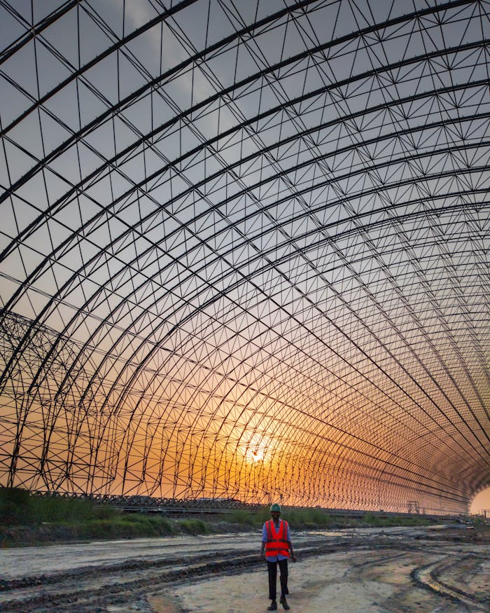 services-04 Engineer standing inside a large metal frame structure at sunset, Bangladesh.