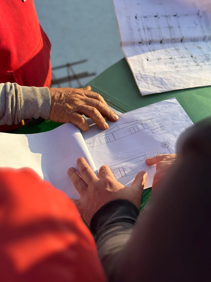services-02 A team of architects examining architectural blueprints at an outdoor construction site.