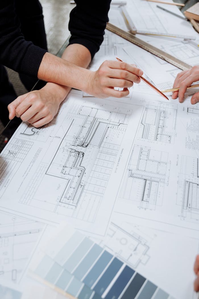 services-03 Architects discussing detailed blueprints and schematics at a table.